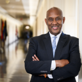 Congressman Dwight Evans is in professional attire and is standing in a hallway.